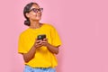 Young cheerful Indian woman laughing holding mobile phone stands in studio Royalty Free Stock Photo