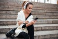 Young cheerful lady sitting on steps outdoors listening music Royalty Free Stock Photo