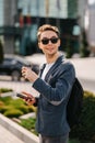 Young Cheerful man in city drinking cup of coffee to go and looking somewhere