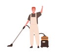 Young cheerful man in office cleaning service, janitor uniform vacuuming. Guy hoover up floor with vacuum cleaner Royalty Free Stock Photo