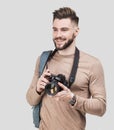 Young cheerful man photographer takes images with digital camera. Isolated on gray background