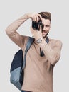 Young cheerful man photographer takes images with digital camera. Isolated on gray background Royalty Free Stock Photo