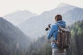 Young cheerful man photographer taking photographs with digital camera in mountains. Travel and active lifestyle concept Royalty Free Stock Photo