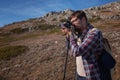 Young man taking photographs with digital camera in a mountains. Royalty Free Stock Photo