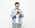 young cheerful man standing isolated over white background, using mobile phone Royalty Free Stock Photo