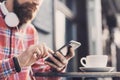 Young man texting on his smartphone in the city. Close up of cheerful adult using mobile phone in a cafe