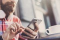 Young man texting on his smartphone in the city. Close up of cheerful adult using mobile phone in a cafe