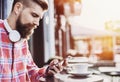 Young cheerful man using smartphone in the city. Close up of cheerful adult using mobile phone in a cafe