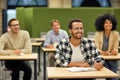 Young cheerful mixed race male office worker sitting listening to coach during seminar or training and smiling while Royalty Free Stock Photo