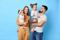 Young cheerful mom and dad holding kids in arms and posing to the camera