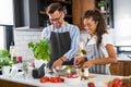 Happy multiethnic couple preparing home made tomato and basil pasta. Cooking at home