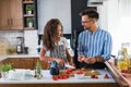 Happy multiethnic couple preparing home made tomato and basil pasta. Cooking at home