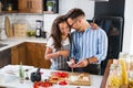 Happy multiethnic couple preparing home made tomato and basil pasta. Cooking at home