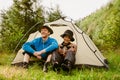 Cheerful tourist couple drinking tea while sitting at camping tent in green forest Royalty Free Stock Photo