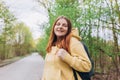 Young cheerful redhaired woman enjoying spring day in park. Young woman hiking and going camping in nature. Person with