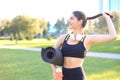 Young cheerful sports woman walking in urban park holding fitness rug Royalty Free Stock Photo