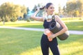 Young cheerful sports woman walking in urban park holding fitness rug Royalty Free Stock Photo