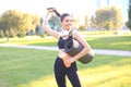 Young cheerful sports woman walking in urban park holding fitness rug Royalty Free Stock Photo