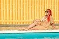 A young cheerful woman with African pigtails sits on the edge of a sunbathing pool. Royalty Free Stock Photo
