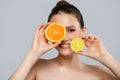 Young cheerful woman with a beautiful smile holds orange and lemon slices. On a blue background Royalty Free Stock Photo