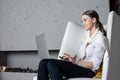 Young cheerful woman content manager or professional writer keyboarding on portable laptop computer, sitting in modern interior ne Royalty Free Stock Photo