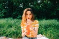 Young cheerful woman with drink, in natural park on picnic, enjoying summer holidays vacation Royalty Free Stock Photo