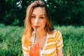 Young cheerful woman with drink, in natural park on picnic, enjoying summer holidays vacation Royalty Free Stock Photo