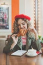 Young cheerful woman eating croissant and drinking coffee in city street cafe Royalty Free Stock Photo