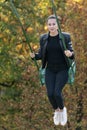 Young cheerful woman goes for a drive on swing in autumn park. Vertical frame