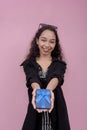A young cheerful woman hands over a small gift, possibly jewelry inside a small wrapped blue box. Royalty Free Stock Photo