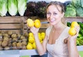 cheerful woman holding lemons in hands in fruit store Royalty Free Stock Photo