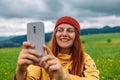 Tourist taking picture on her smartphone from top of mountain. Caucasian woman in hat and with backpack on rock. Travel Royalty Free Stock Photo