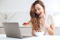 Pretty woman chatting on laptop and eating fruits Royalty Free Stock Photo