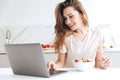 Pretty woman chatting on laptop and eating fruits Royalty Free Stock Photo