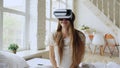 Young cheerful woman wearing virtual reality headset watching 360 VR video movie sitting in the bed at home Royalty Free Stock Photo