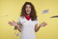 Young cheerful woman wins a lots of cash, over flying cash and yellow background