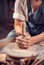 Young and cheerful woman is working on pottery wheel. Artisan production. Close-up.