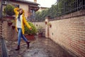 A young cheerful woman in a yellow raincoat is posing for a photo while walking the city on a rainy day. Walk, rain, city Royalty Free Stock Photo