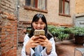 Young asian girl using mobile phone while sitting in cafe outdoors Royalty Free Stock Photo