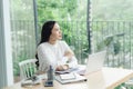 Young cheery happy positive cute beautiful business woman sit indoors in office using laptop computer Royalty Free Stock Photo