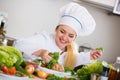 Female cook arranging herbs decoration on plate with salad