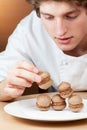 Young chef confectioner puts sponge cakes on plate Royalty Free Stock Photo