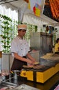 Young chef grills meat and fish on skewers, Singapore