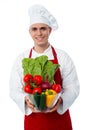 Young chef holding vegetables bowl