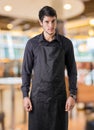 Young chef or waiter wearing black apron in restaurant Royalty Free Stock Photo