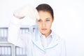 Young chemical female researcher holding glass tube with blue fl