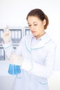 Young chemical female researcher with vials and flasks makes some experiments in laboratory