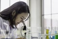 Young chemist woman looking through microscope, working at the laboratory, chemical testing in lab, concept for improving safety Royalty Free Stock Photo