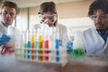 Young chemistry students in a laboratory doing an experiment with colorful chemicals. Science, chemistry, lab, people