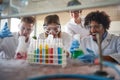 Young chemistry students in a laboratory are excited while watching colorful chemical reactions. Science, chemistry, lab, people